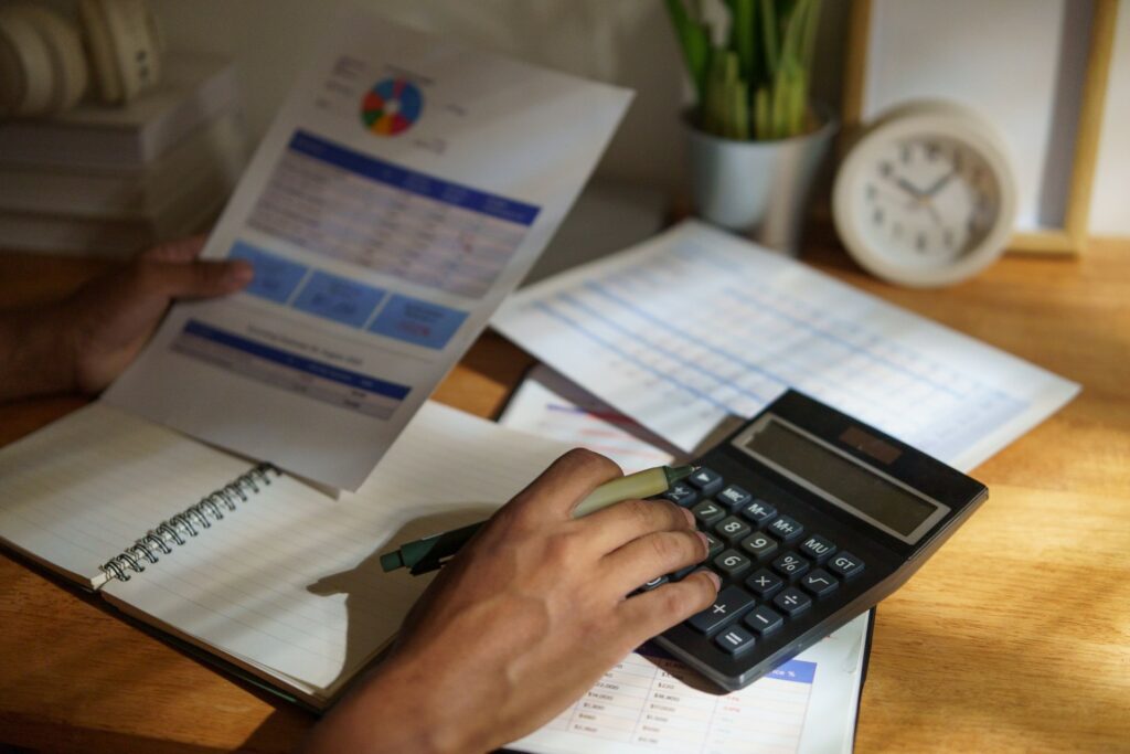 A business owner working through printed cost statements with a calculator, putting a number on what a process costs.