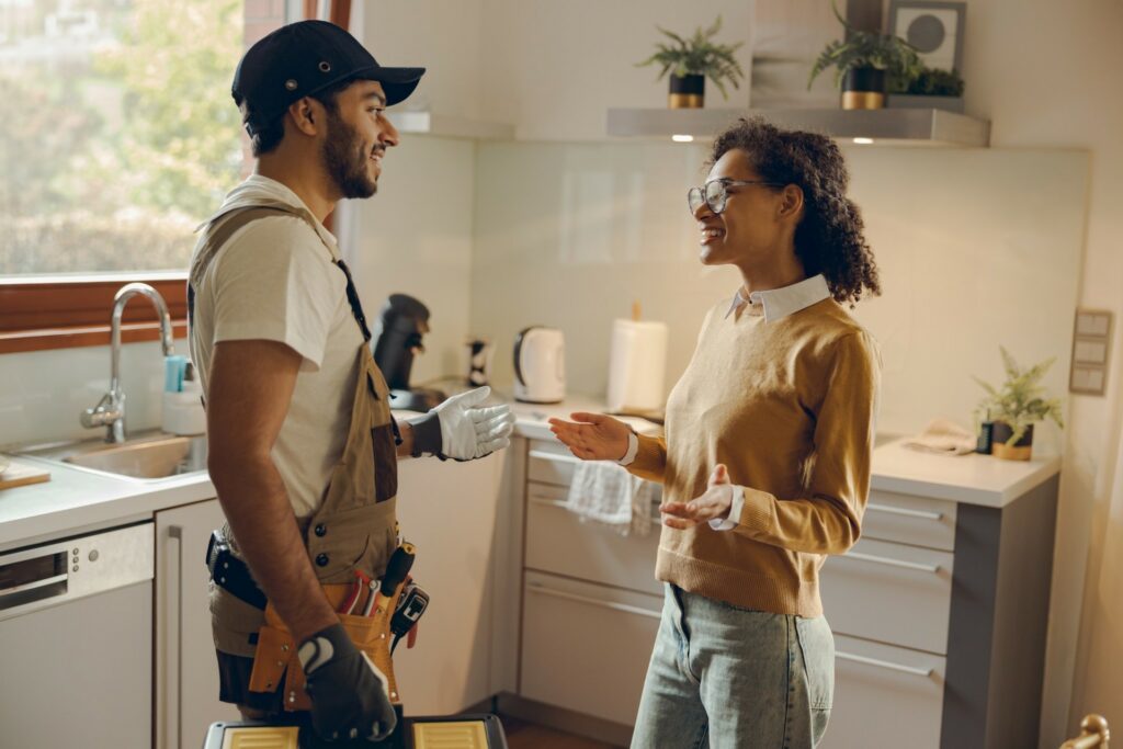 A tradesperson and a homeowner talking in a kitchen after a job, the kind of visit a detailed local review describes.