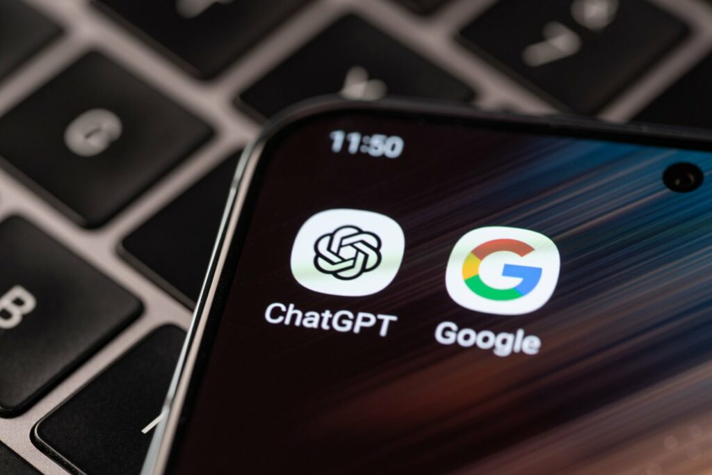 ChatGPT and Google app icons side by side on a smartphone screen resting on a laptop keyboard